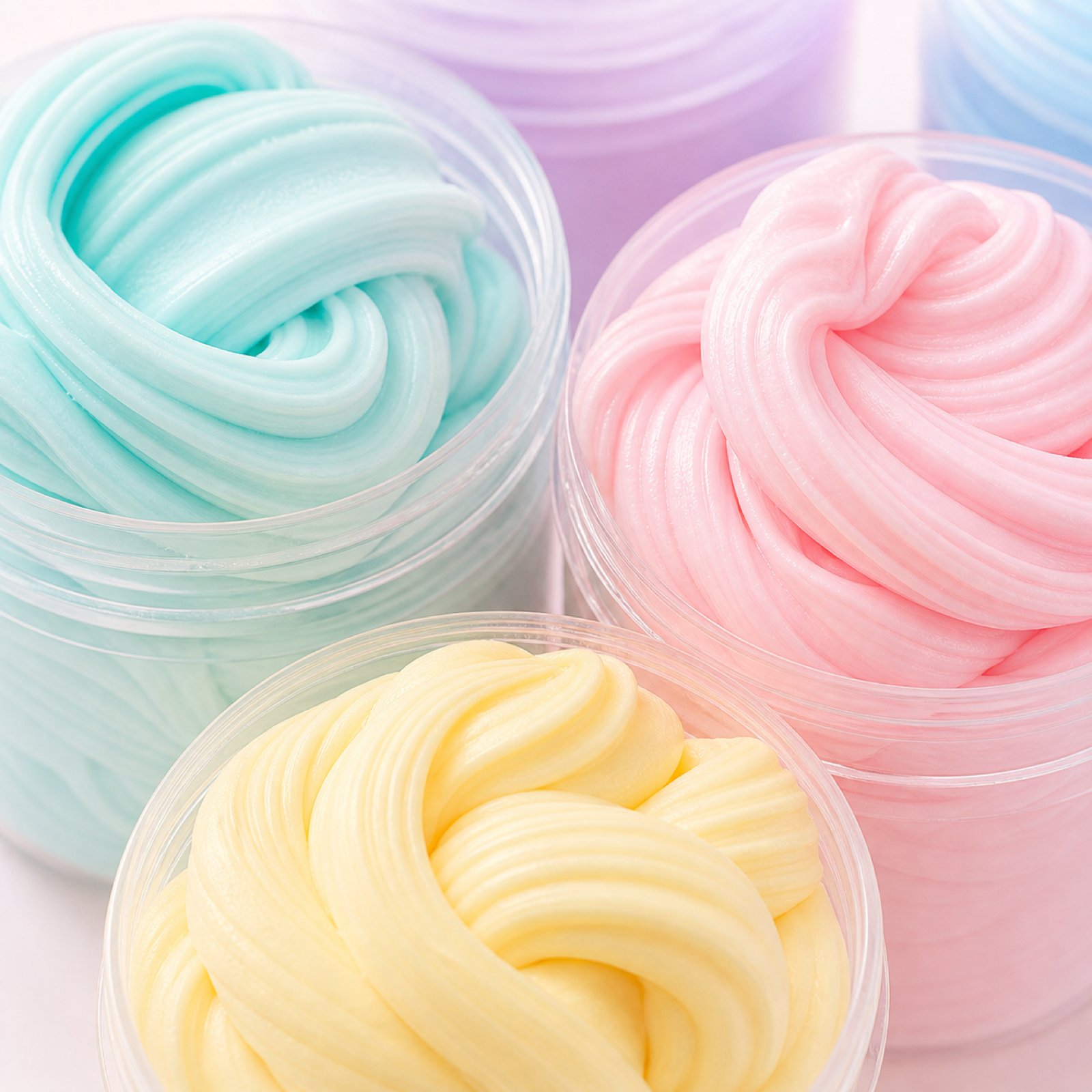 Close-up of pastel butter slime swirl textures in open tubs