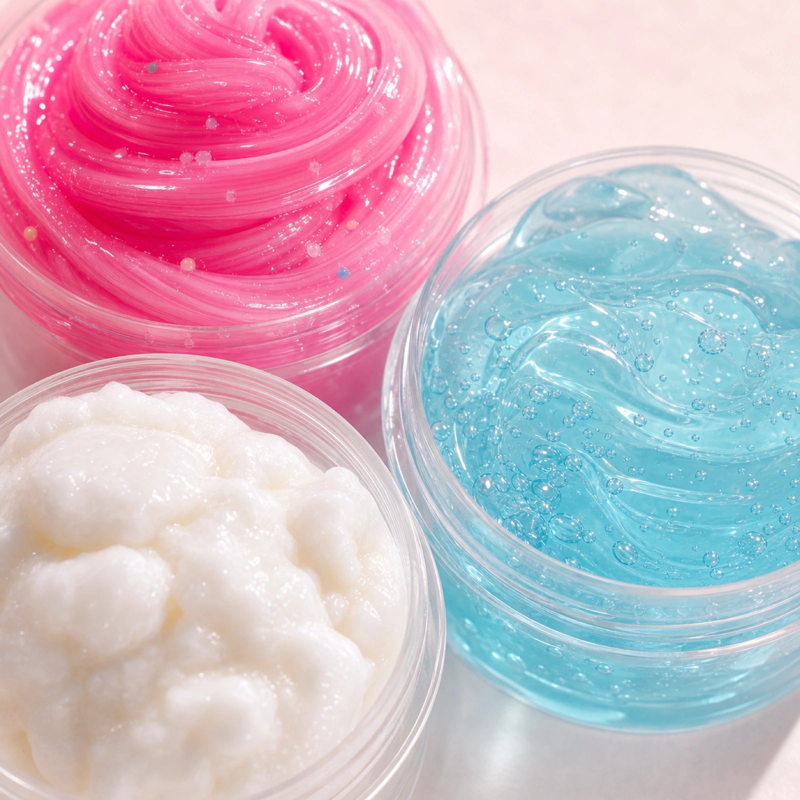 Close-up of pink blue and white slime textures in open tubs