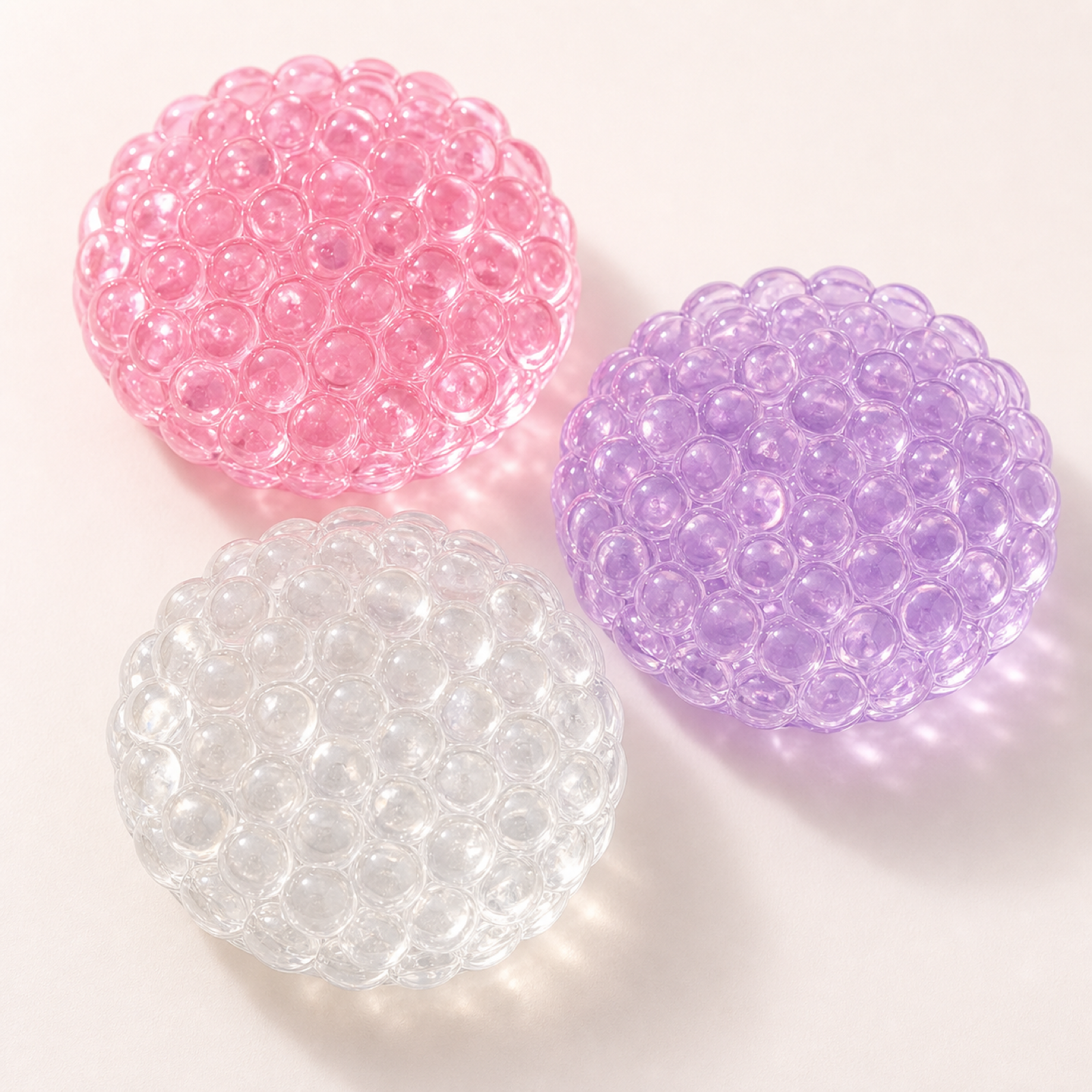 Flat bead chatter ball stress fidgets in pink purple and clear on a clean background